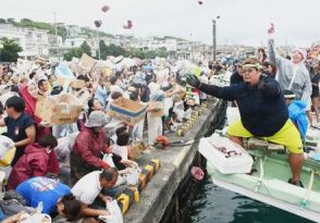 船から陸へカツオの切り身を振りまく漁師　ゲットしようと段ボール箱を抱えて群がる人々　沖縄・伊良部島の海神祭で「大盤振る舞い」